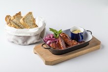 Smoked sausages roasted with dark beer and vegetables, served with tarragon mustard and bread from our oven